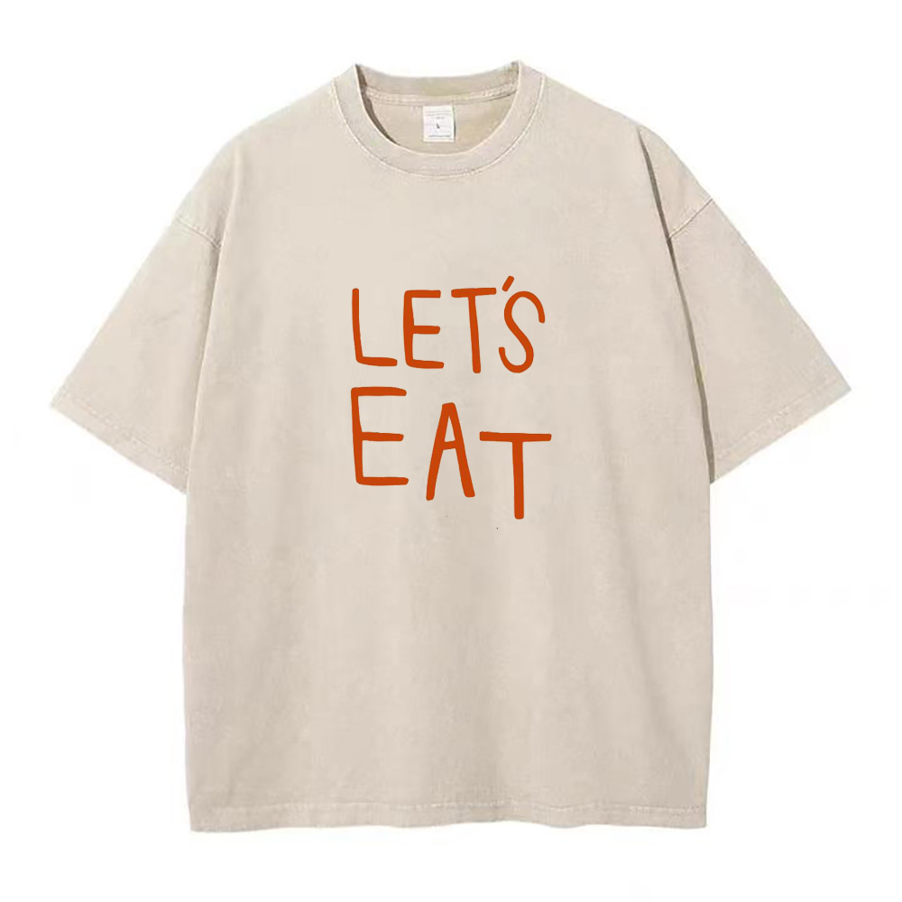 Oversized beige crew neck t-shirt with the text 'LET'S EAT' written in orange on the front.