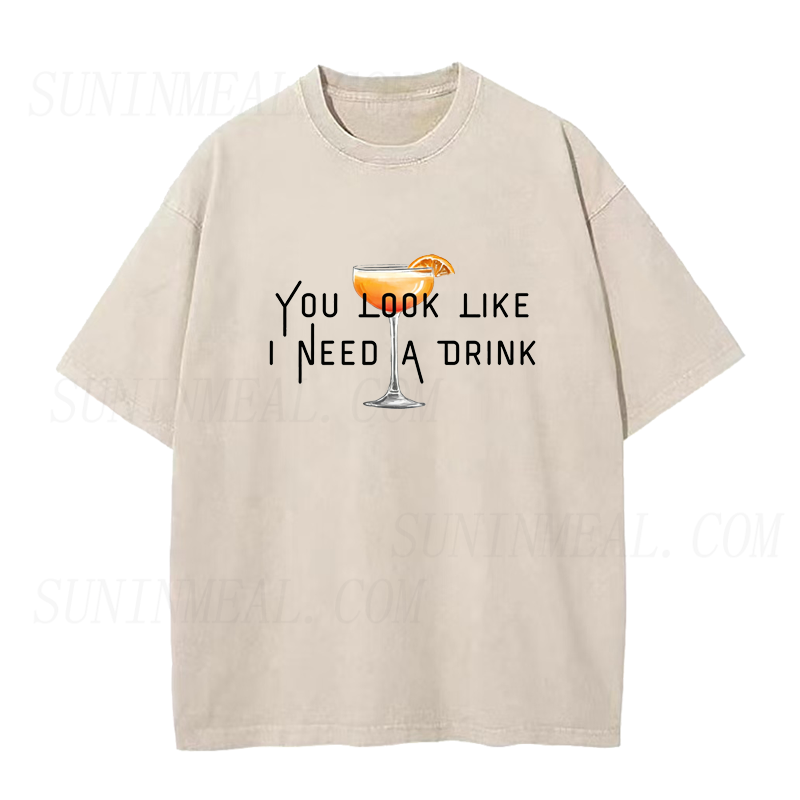 Beige t-shirt with a graphic and text 'You look like I need a drink' on a white background
